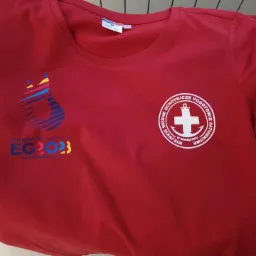 Czerwona koszulka z nadrukiem logo Kraków Małopolska EG2023 oraz logo Miejskie Ochotnicze Pogotowie Ratunkowe w Oświęcimiu.