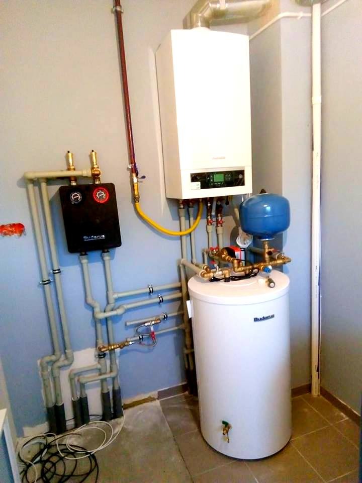 Zmontowana instalacja centralnego ogrzewania z piecem dwufunkcyjnym, zasobnikiem wody i czarną skrzynką rozdzielczą w Radzyminie, widoczne liczne rury i zawory.