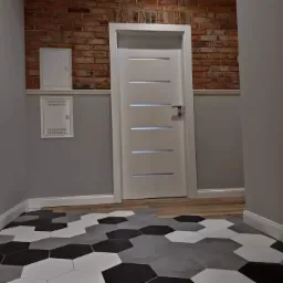 Przedpokój z podłogą wyłożoną heksagonalnymi płytkami w odcieniach szarości, bieli i czerni, białe drzwi z poziomymi przeszkleniami, ściana z cegły i szare panele ścienne z białą listwą przypodłogową.
