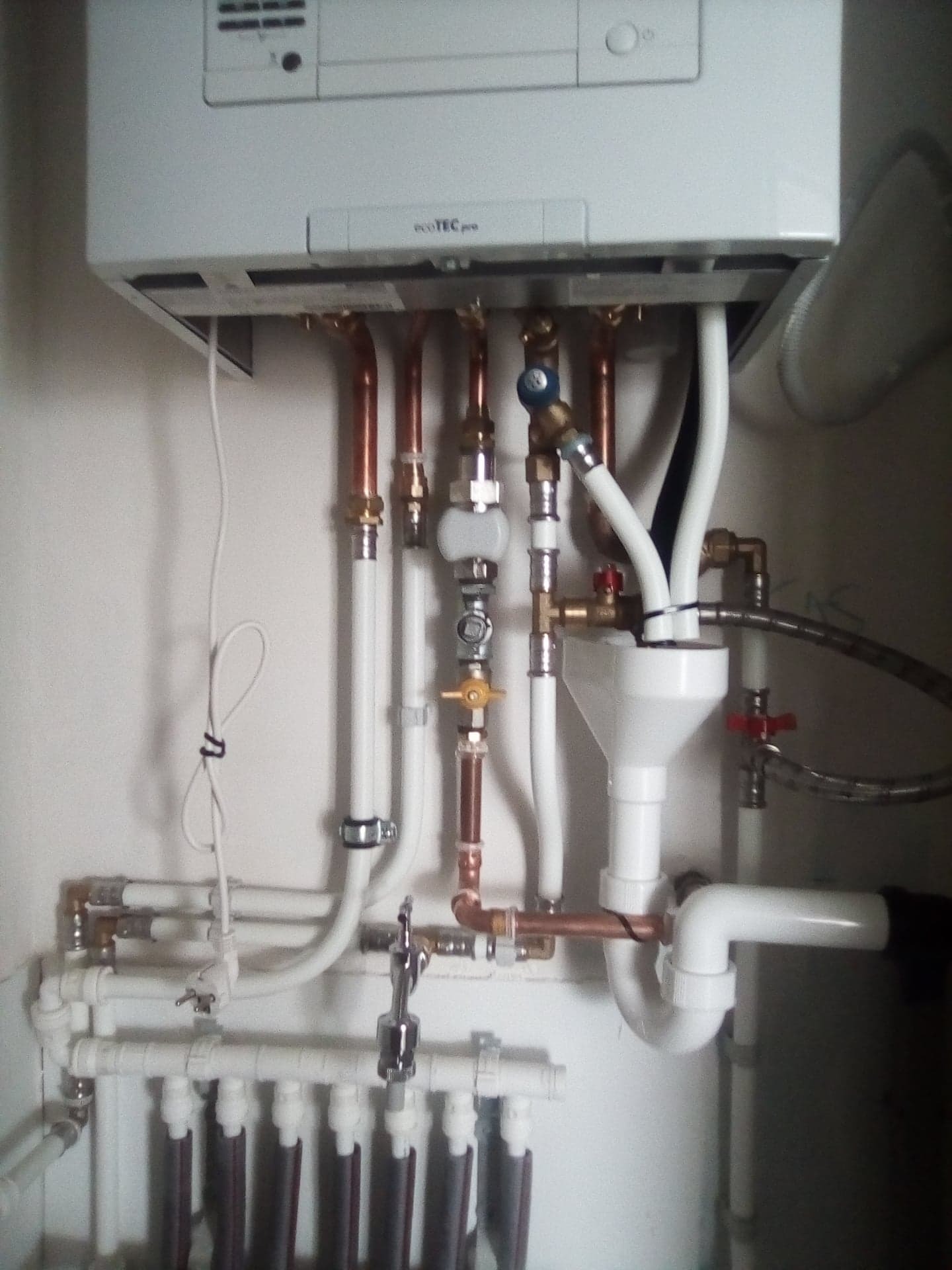 Szczegółowe przyłącze pieca gazowego EcoteC pro z widocznymi rurami miedzianymi i białymi PCV, zainstalowane w Gdańsku.