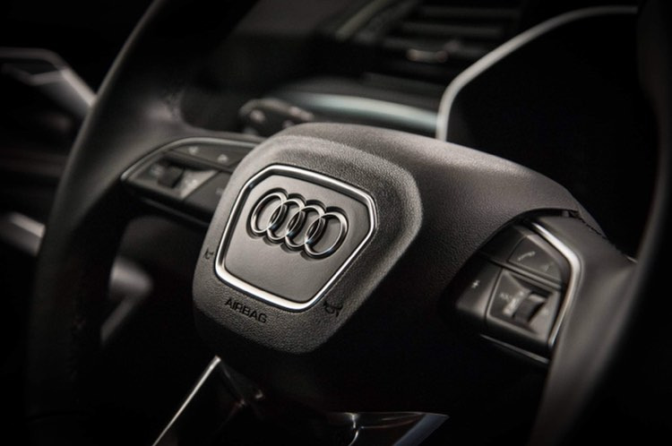 Czarna skórzana kierownica Audi z chromowanym logo na tle wnętrza samochodu w Tychach.