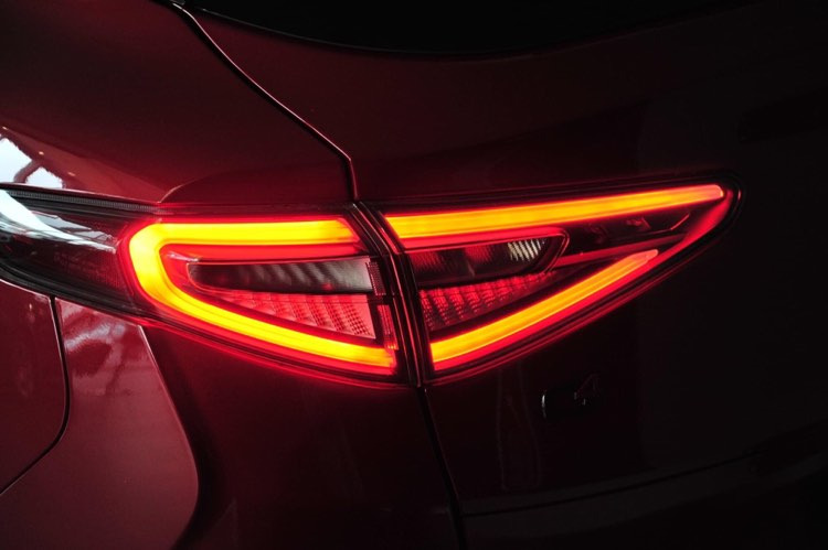Świecący, nowoczesny tylny reflektor samochodu w kolorze głębokiej czerwieni z wyraźnie zarysowanymi liniami LED.