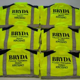 Sześć identycznych, fluorescencyjnych kurtek roboczych z nadrukowanym logo firmy 'BRYDA Posadzki Przemysłowe Wylewki KROSNO' i elementami odblaskowymi.