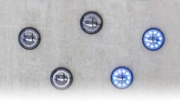 Dekoracyjne oświetlenie sufitowe w kształcie okrągłych lamp z różnymi kolorami światła, zamontowane na szarej, teksturowanej powierzchni.