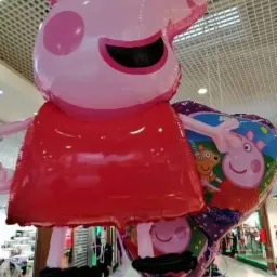Balony foliowe w kształcie świnki Peppy i serca z motywami z bajki, unoszące się w przestrzeni galerii handlowej w Sosnowcu.