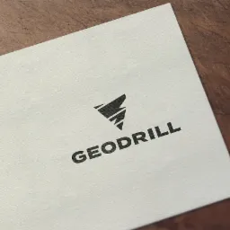 Logo firmy Geodrill w kolorze czarnym, umieszczone na białej wizytówce leżącej na drewnianym tle.