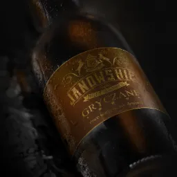 Butelka ciemnego piwa rzemieślniczego z etykietą w odcieniach złota i brązu, pokryta kroplami wody, na ciemnym tle.