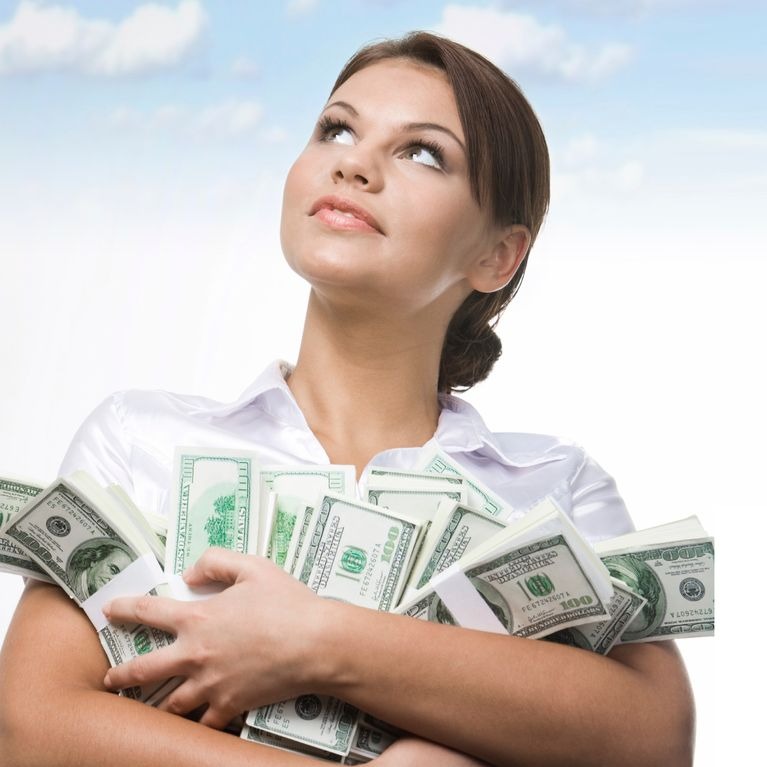 Kobieta w białej koszuli, obejmująca ramionami pliki banknotów studolarowych, spoglądająca w górę na tle błękitnego nieba z chmurami.