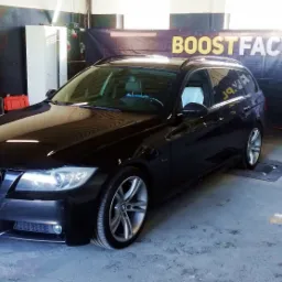 Czarny samochód BMW E91 kombi na stanowisku z logo Boostfactory.pl w tle, prawdopodobnie podczas pomiaru mocy po chiptuningu.