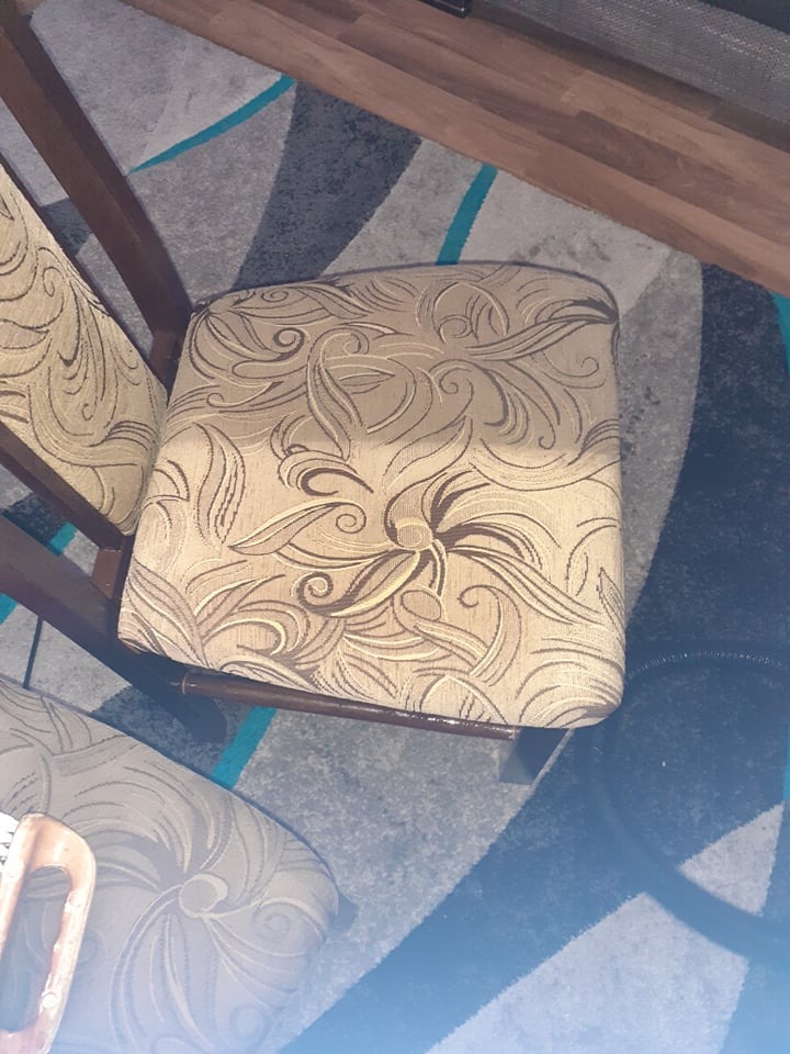 Krzesło z beżową tapicerką w kwiatowe wzory, stojące na dywanie w geometryczne wzory, widoczne z góry.