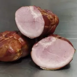 Trzy wędzonki ułożone jedna na drugiej, dwie z nich przekrojone, ukazujące różowe wnętrze na tle metalowej powierzchni.