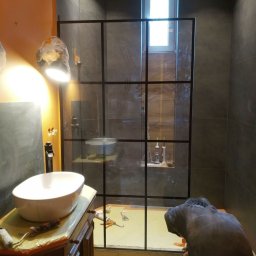 Konrad Kwietniewski - Montaż kabiny prysznicowej z czarnymi szprosami w łazience w trakcie prac w Łodzi, widoczna biała umywalka nablatowa, narzędzia i silikony.