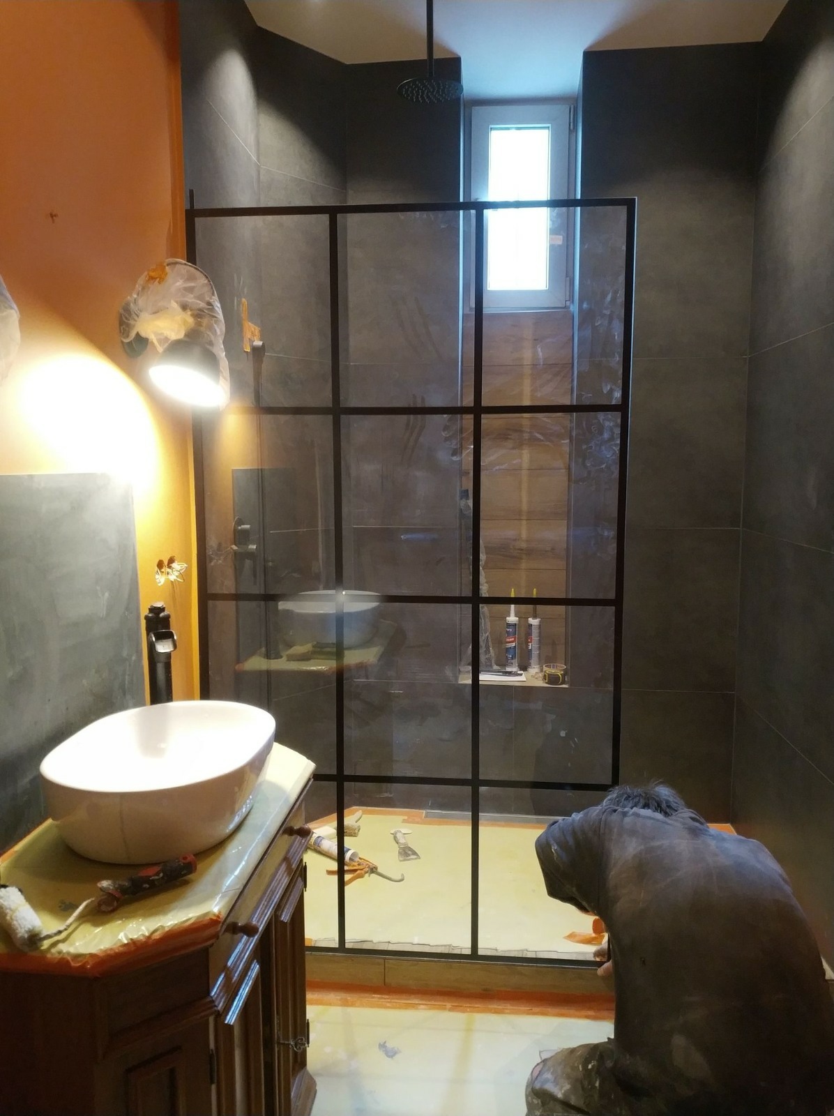 Montaż kabiny prysznicowej z czarnymi szprosami w łazience w trakcie prac w Łodzi, widoczna biała umywalka nablatowa, narzędzia i silikony.