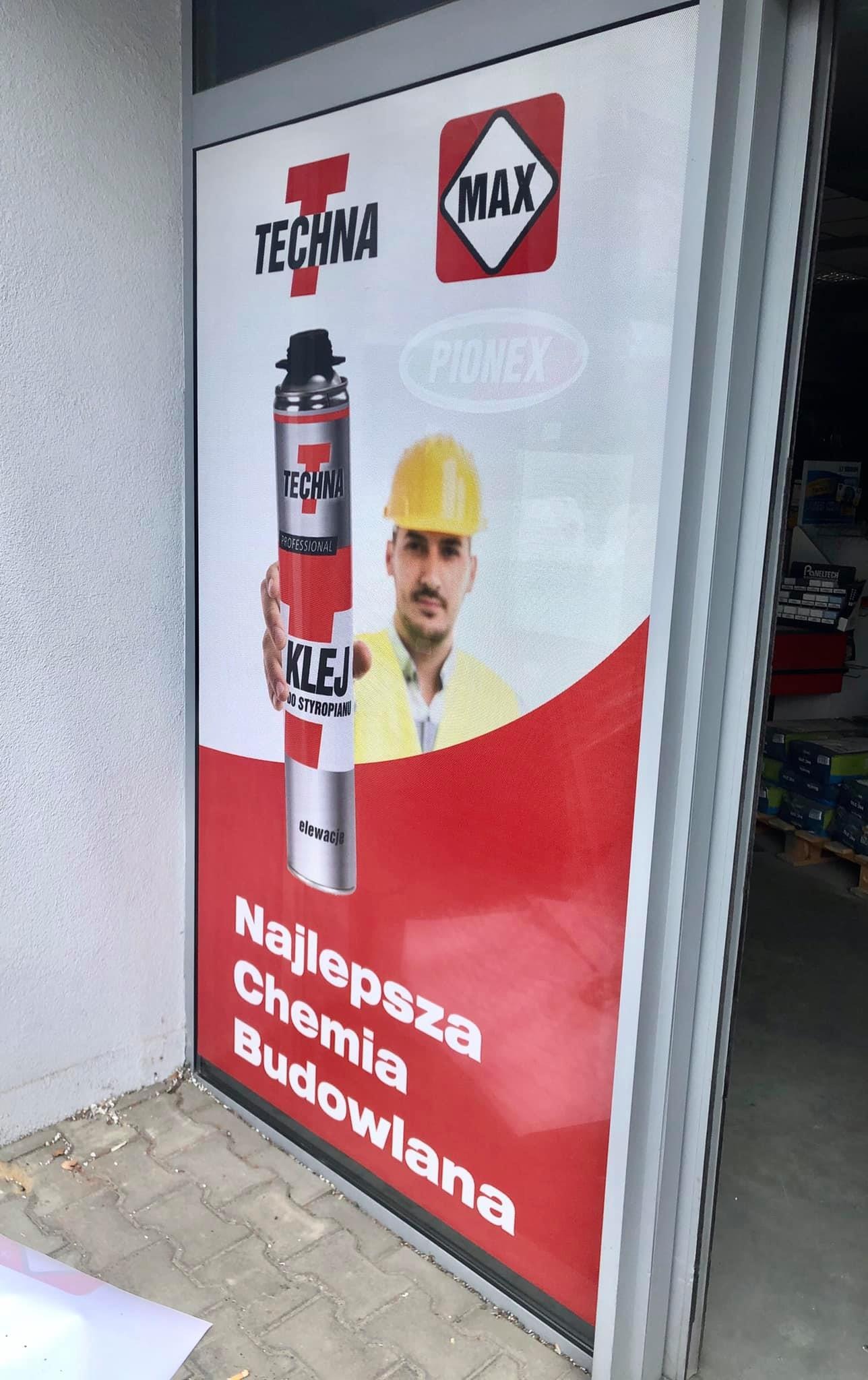 Tablica reklamowa z wizerunkiem pracownika w kasku i puszką kleju do styropianu marki Techna, hasłem 'Najlepsza Chemia Budowlana' i logotypami Techna Max i Pionex.