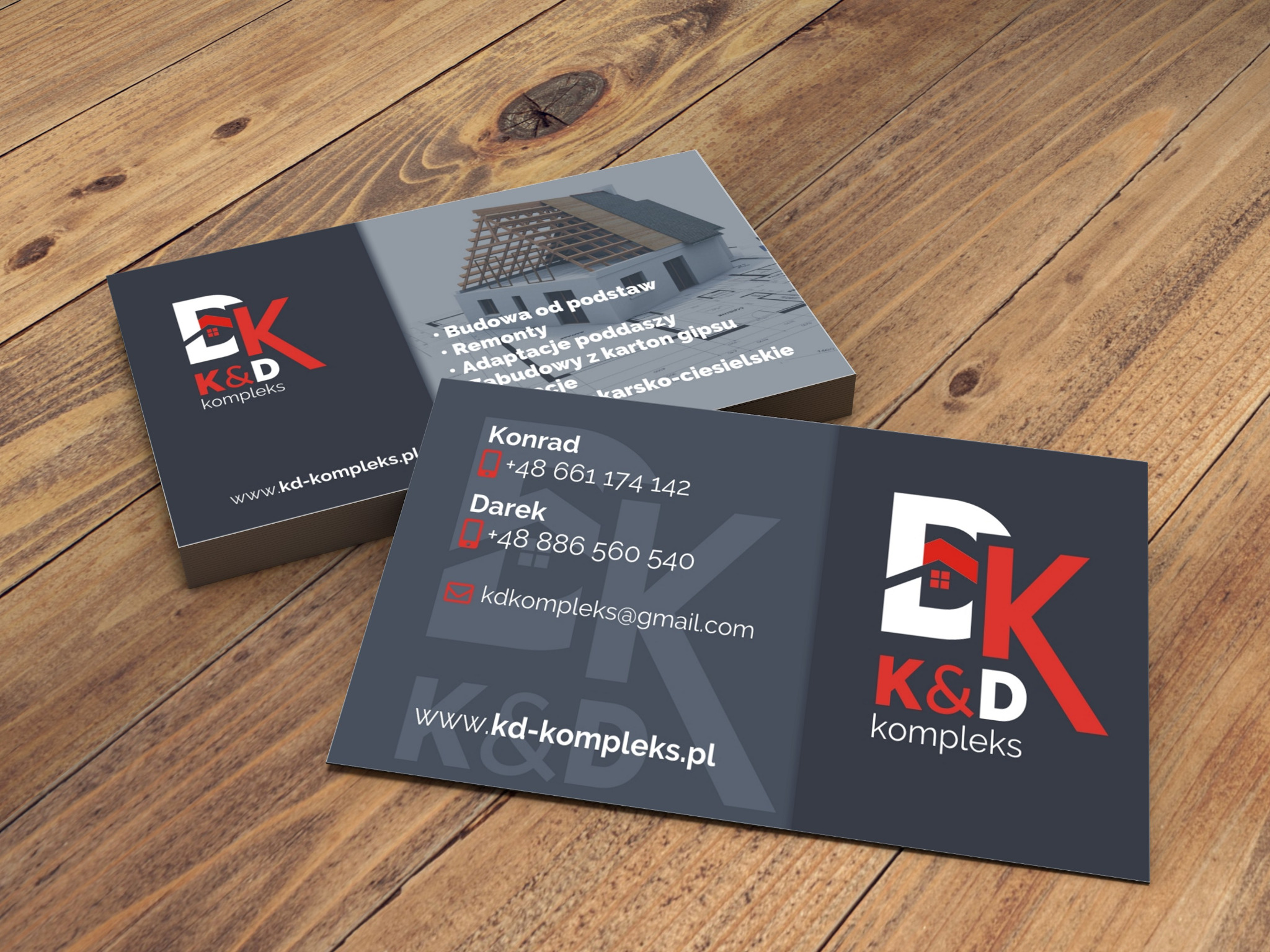 Stos wizytówek firmy budowlanej K&D kompleks na drewnianym biurku, prezentujące logo z motywem dachu, dane kontaktowe oraz zakres usług: budowa, remonty i adaptacje poddaszy.
