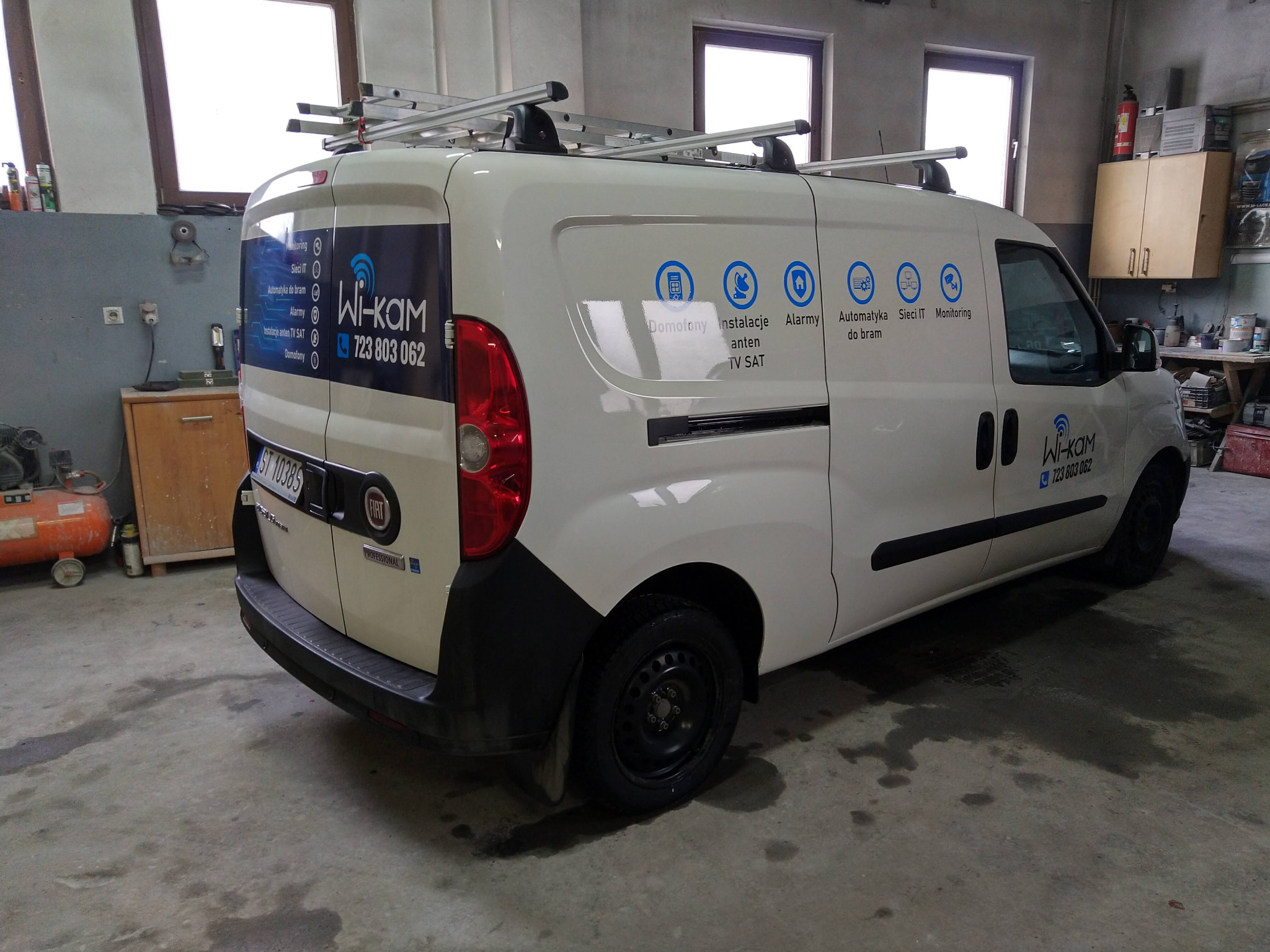 Biały samochód dostawczy z logo firmy Wi-Kam i informacjami o usługach: domofony, instalacje anten TV SAT, alarmy, automatyka do bram, sieci IT, monitoring.