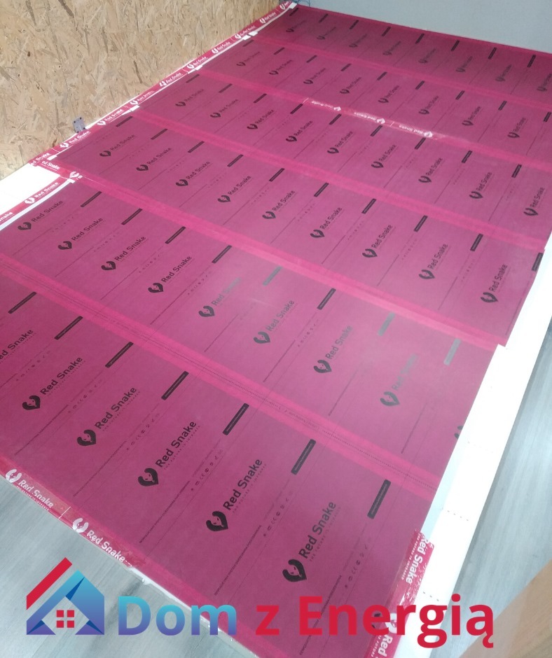 Równomiernie rozłożone panele izolacyjne Red Snake na podłodze, gotowe do dalszych prac wykończeniowych, widoczne drewniane elementy konstrukcyjne ściany w tle.