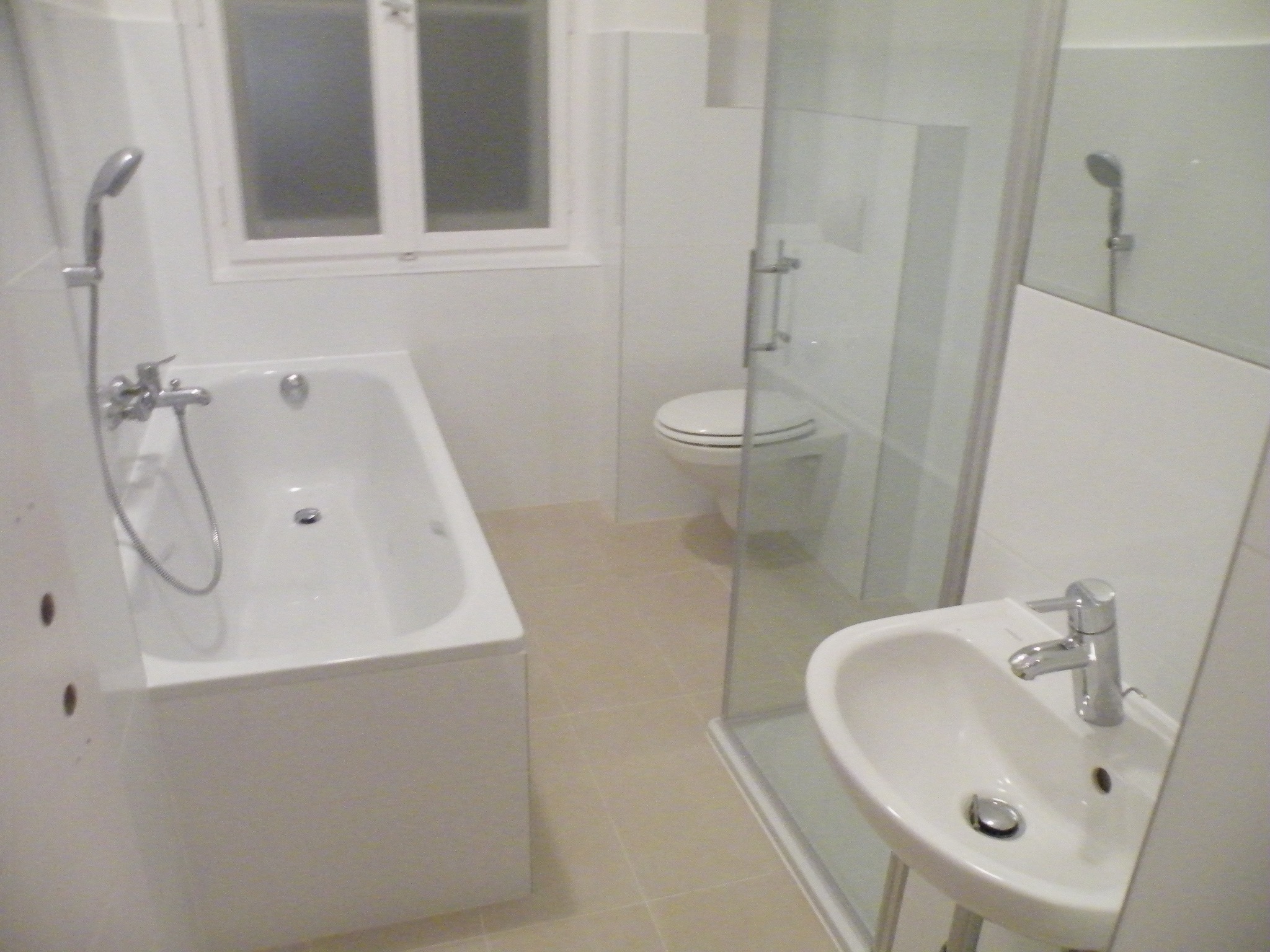 Jasna łazienka we Wrocławiu po remoncie, z wanną, umywalką narożną i kabiną prysznicową za szybą.