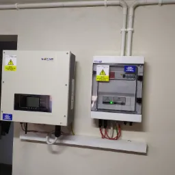 Zamontowany inwerter Sofar Solar obok skrzynki z bezpiecznikami instalacji fotowoltaicznej, widoczne kable i oznaczenia ostrzegawcze.