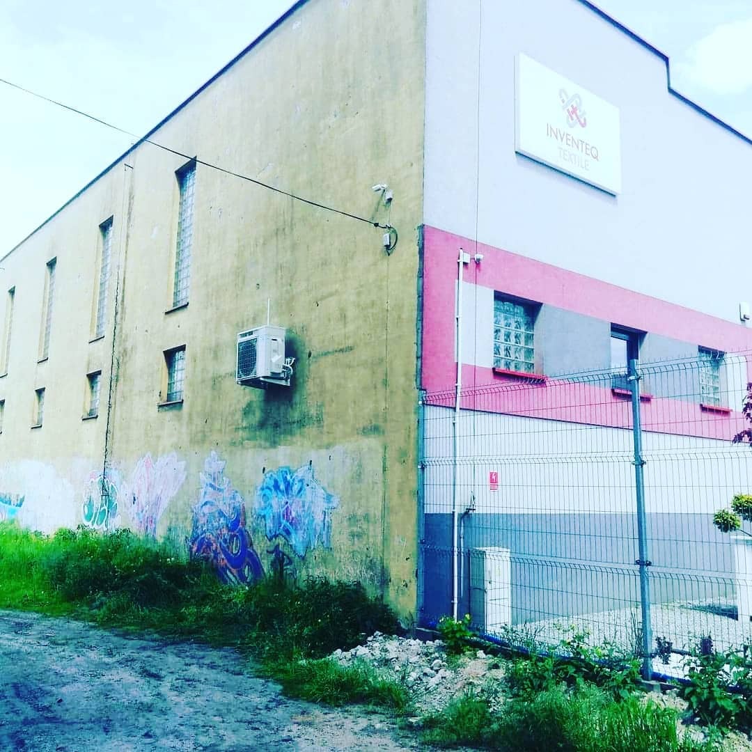 Zewnętrzna jednostka klimatyzacji zamontowana na bocznej ścianie budynku z graffiti, widok z poziomu gruntu.