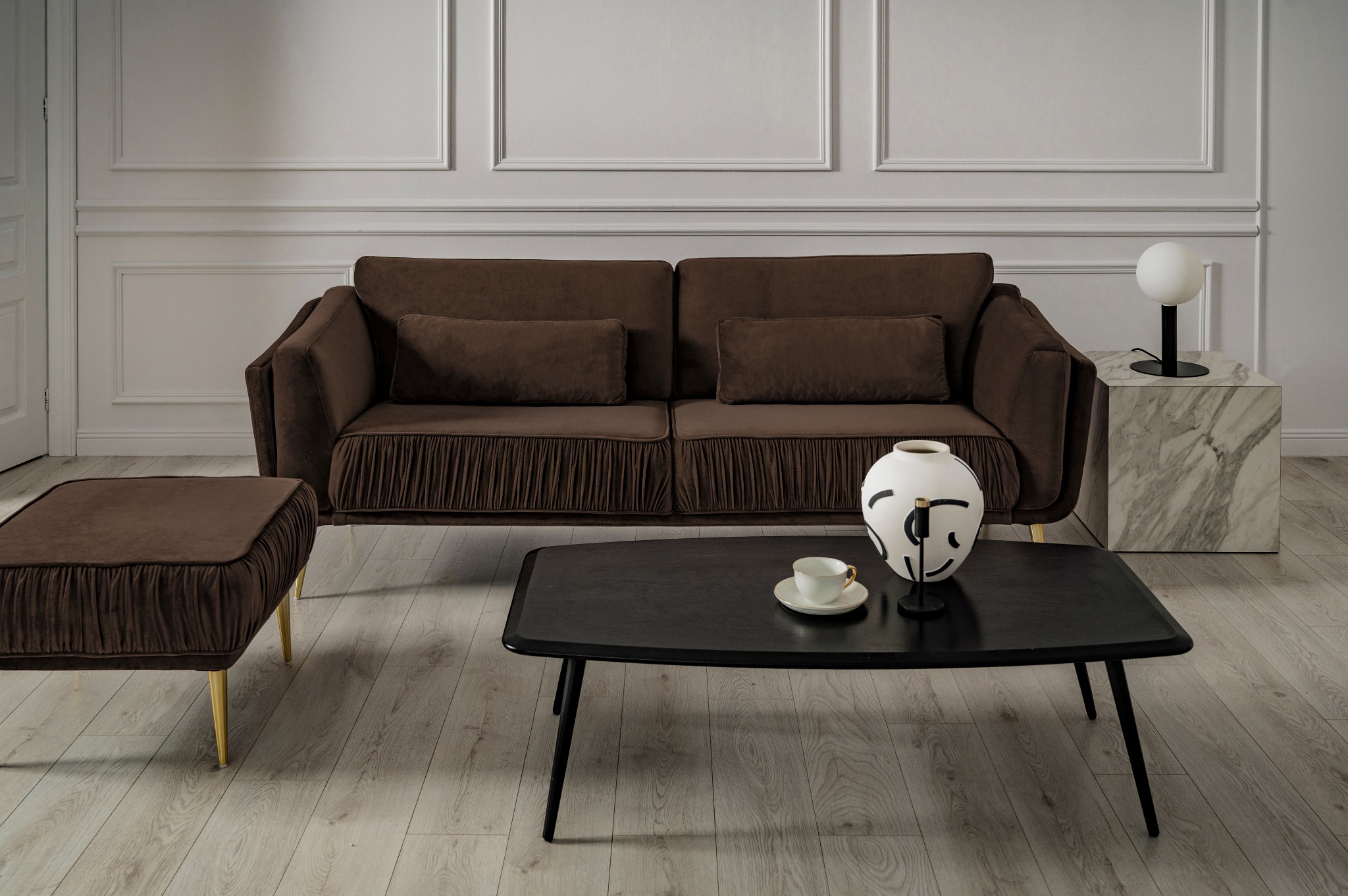 Salon w Prusicach z brązową sofą z marszczeniami, czarnym stolikiem kawowym, marmurowym stolikiem bocznym i dekoracyjną wazą.