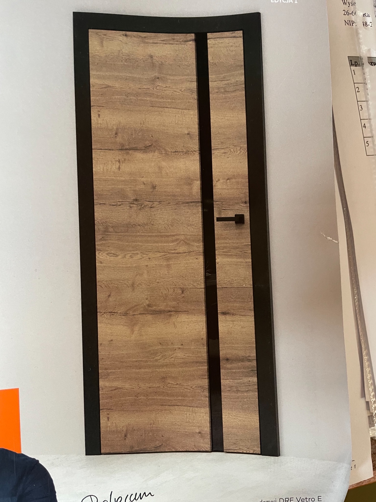 Prezentacja drzwi wewnętrznych z okleiną drewnopodobną i czarnymi elementami wykończeniowymi, widoczna na zdjęciu katalogowym z fragmentami tekstu i numeracji.