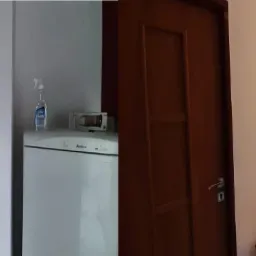 Korytarz w trakcie remontu: ściany wykończone płytami karton gips, widoczna lodówka Amica, drewniana komoda i drzwi.