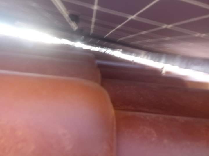 Nietypowe ujęcie paneli słonecznych zamontowanych na dachu z czerwonej dachówki, widok z dołu pod kątem.