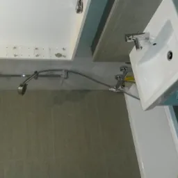 Nowoczesna łazienka w trakcie wykańczania: szare płytki, biała umywalka z szafką i bateria, biała wanna, chromowana bateria prysznicowa z deszczownicą. Widoczne niedokończone elementy montażowe...