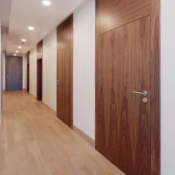 Długi korytarz z ukrytymi, fornirowanymi drzwiami wewnętrznymi z klamkami ze stali nierdzewnej i jasną podłogą panelową, oświetlony szeregiem okrągłych lamp sufitowych.