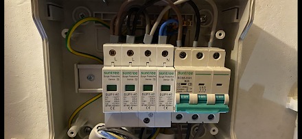 Wnętrze skrzynki elektrycznej z zamontowanymi ogranicznikami przepięć Suntree SUP1-40 i wyłącznikiem BOMA-A01, widoczne kable i przewody.