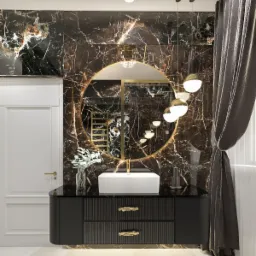 Elegancka łazienka z czarnymi marmurowymi ścianami, okrągłym lustrem w złotej ramie, białą umywalką nablatową na czarnej szafce z ryflowanymi frontami i złotymi uchwytami, oświetlona wiszącymi...
