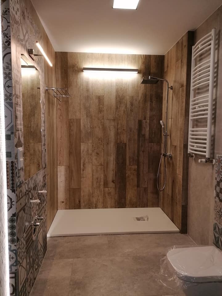 Nowoczesna łazienka z kabiną prysznicową typu walk-in wyłożoną panelami imitującymi drewno, oświetleniem LED i grzejnikiem drabinkowym, z elementami dekoracyjnej mozaiki na ścianach.