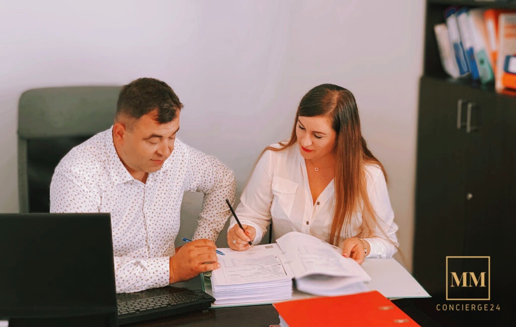 Dwoje prawników analizuje dokumenty przy biurku, kobieta podpisuje umowę czarnym długopisem, obok laptop i segregatory.