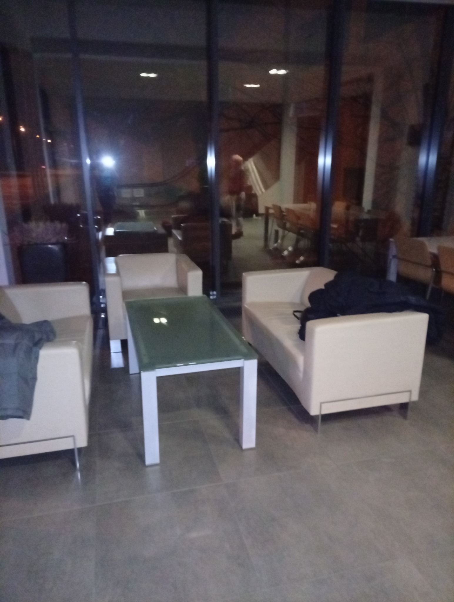 Wnętrze biurowe w Kołobrzegu po sprzątaniu: jasne sofy, szklany stolik, duże okna. Widoczne odbicia w szybach. Czysta podłoga z płytek.