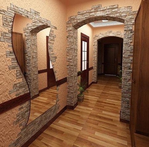 Aranżacja korytarza z dekoracyjnym kamieniem wokół łukowatych przejść i lustra, drewniana podłoga, beżowe ściany o fakturze baranka.