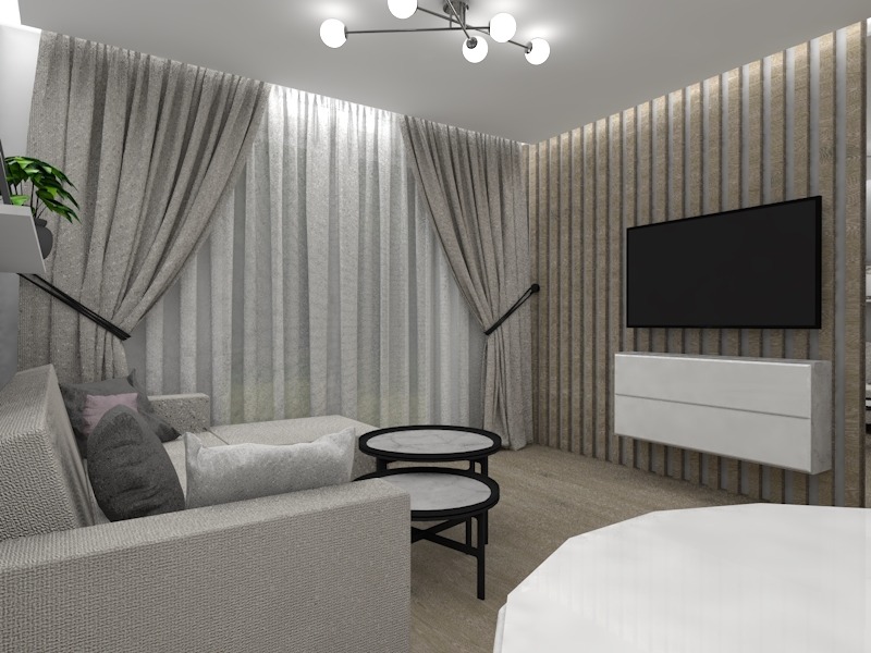 Salon z aneksem kuchennym w nowoczesnym stylu. Widok na szarą sofę z poduszkami, okrągłe stoliki kawowe z marmurowymi blatami oraz ścianę z telewizorem i wiszącą białą komodą. Zasłony w oknach...