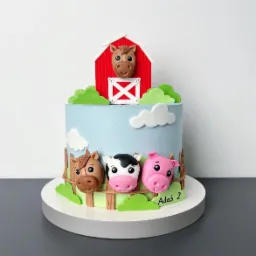 Tort urodzinowy w stylu farmy z figurkami konia, krowy i świni, dekorowany czerwoną stodołą i białymi chmurami, na białym podeście.