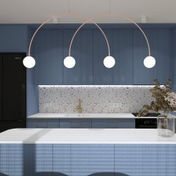 2 RAZY K - Niebieska kuchnia z wyspą i czarną lodówką. Nad wyspą lampa z czterema białymi kulami. Na blacie wazon z kwiatami. Ściana nad blatem wykończona mozaiką.