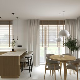 2 RAZY K - Jasna kuchnia z wyspą i okrągłym stołem w Gdańsku. Minimalistyczny design, drewniane żaluzje i białe zasłony. Nowoczesne oświetlenie i subtelna roślinność.