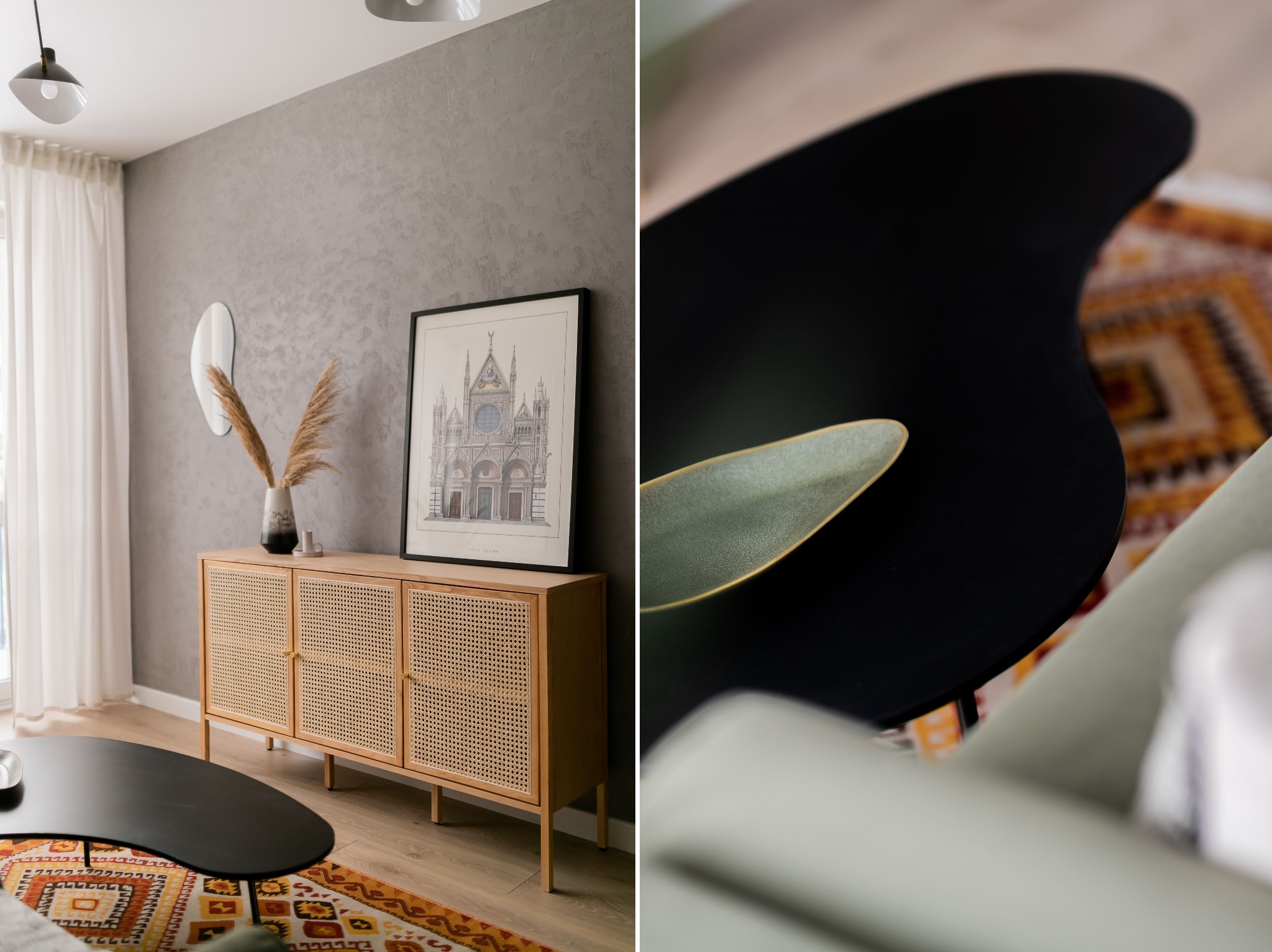 Jasny pokój dzienny z komodą z rattanu, czarnym stolikiem kawowym o nieregularnym kształcie oraz dywanem w etniczne wzory. Na komodzie wazon z suszonymi trawami i grafika w czarnej ramie.