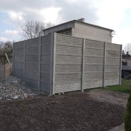 PHU FELIX Weronika Kazimierska - Nowo postawione, szare ogrodzenie z prefabrykatów betonowych o wzorze cegieł, widoczne na tle domu i pochmurnego nieba, z niewielkim stosem gruzu u podstawy.