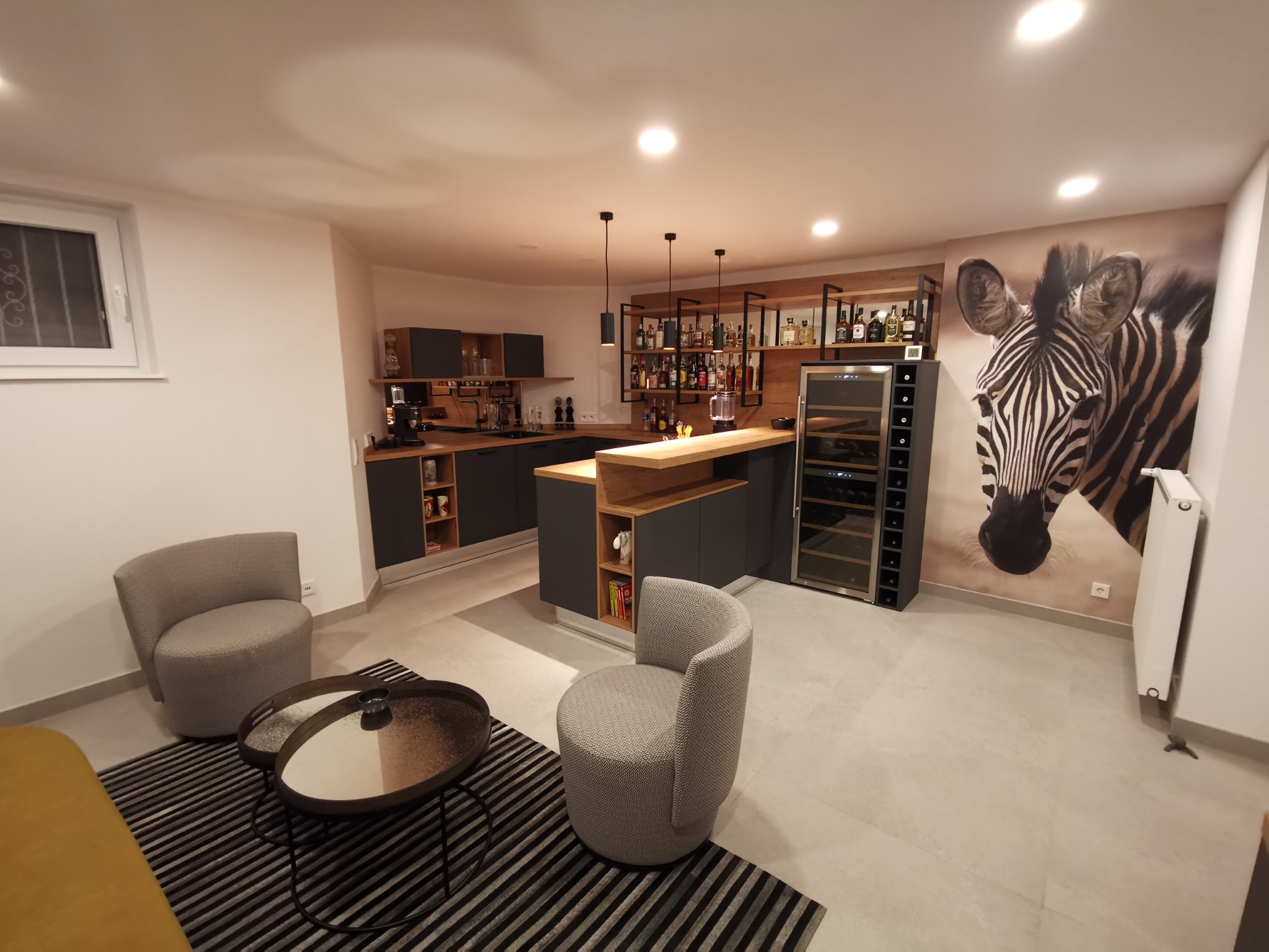 Nowoczesna aranżacja wnętrza w Węgrach z aneksem kuchennym, barkiem z oświetleniem punktowym i dekoracyjną tapetą z motywem zebry.