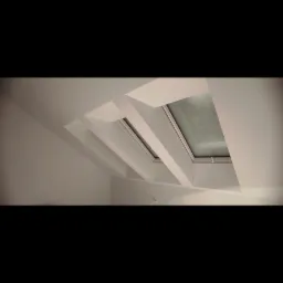 Białe poddasze z oknem dachowym, widoczne elementy konstrukcyjne i skos dachu, świeżo wykończone wnętrze.