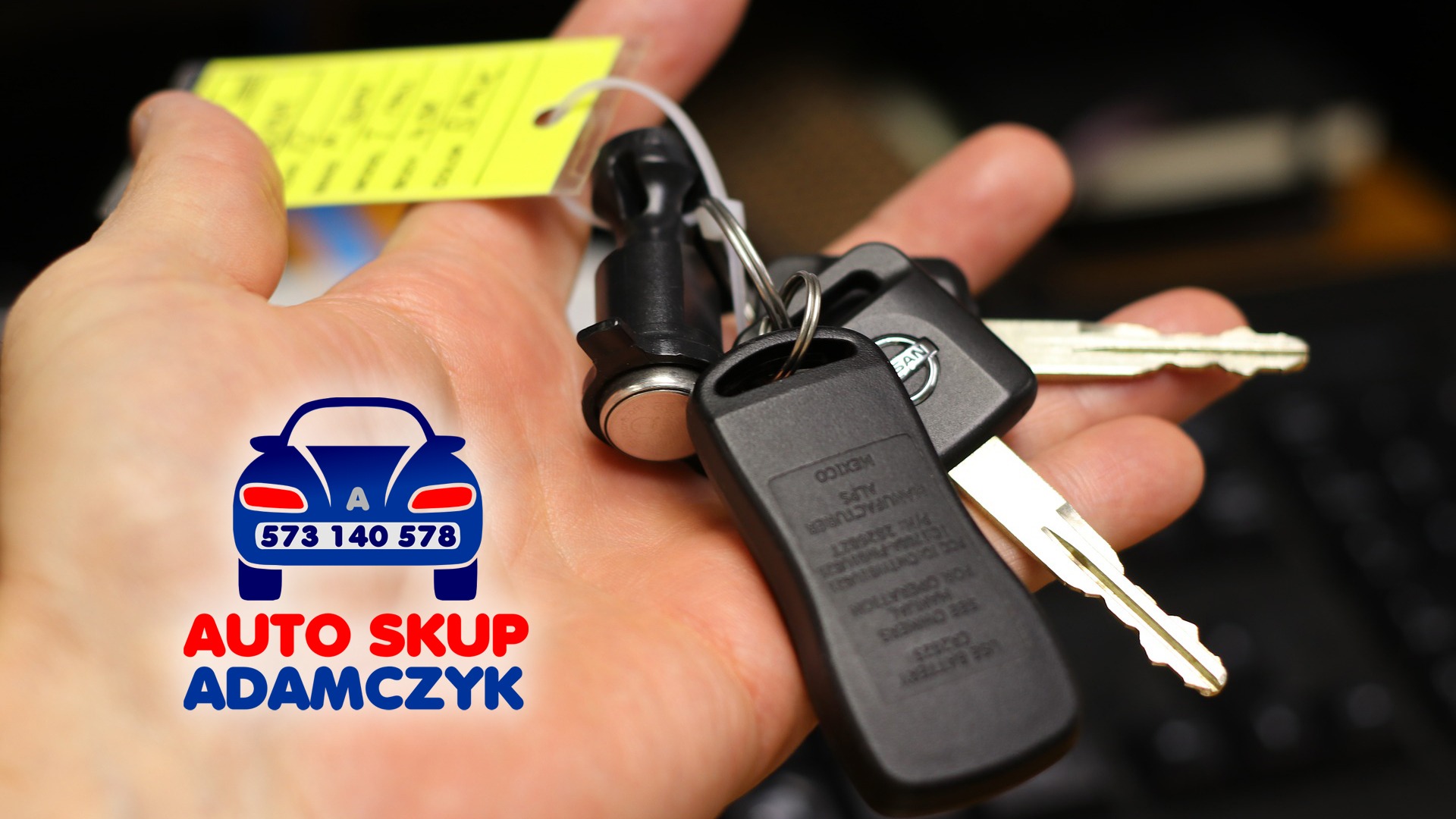 Dłoń trzyma pęk kluczy samochodowych z żółtą zawieszką, logo firmy skupującej pojazdy w rogu.