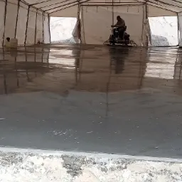 Pracownik w Sieradzu wyrównuje powierzchnię posadzki jastrychowej za pomocą zacieraczki mechanicznej wewnątrz namiotowej konstrukcji.