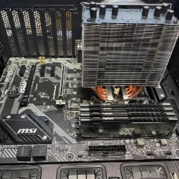 Płyta główna MSI z zainstalowanym chłodzeniem procesora typu tower z miedzianymi rurkami cieplnymi i czterema modułami pamięci RAM Viper, zamontowana w obudowie komputera.