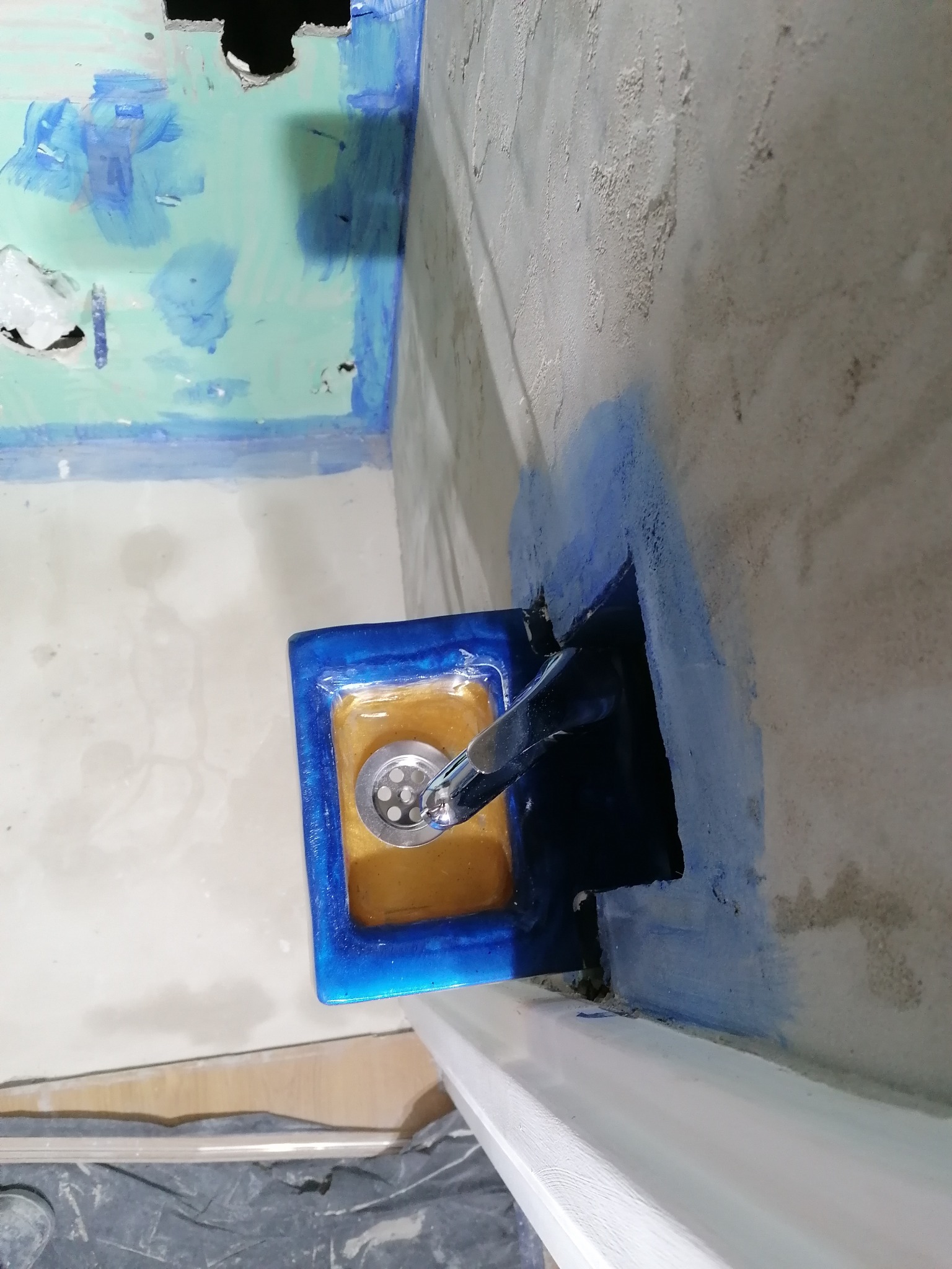 Montaż umywalki w łazience w trakcie remontu, widoczne ślady malowania na ścianach, zabezpieczona podłoga.