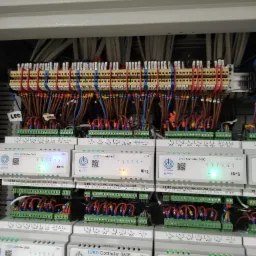 Rozbudowana szafa sterownicza z modułami IUVO Controller 0806, liczne przewody podłączone do listew zaciskowych, widoczne diody sygnalizacyjne i oznaczenia ID modułów.