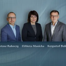 Portret grupowy trzech prawników: Bartosz Rakoczy w niebieskiej marynarce, Elżbieta Manicka w czarnej marynarce w paski oraz Krzysztof Bukowski w szarej marynarce na tle szarej ściany.